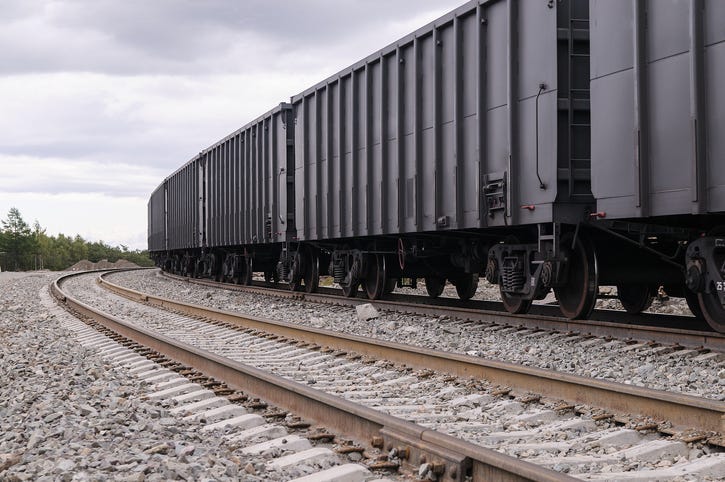Gray Rail Cars Travel Down Train Tracks - Getty Images