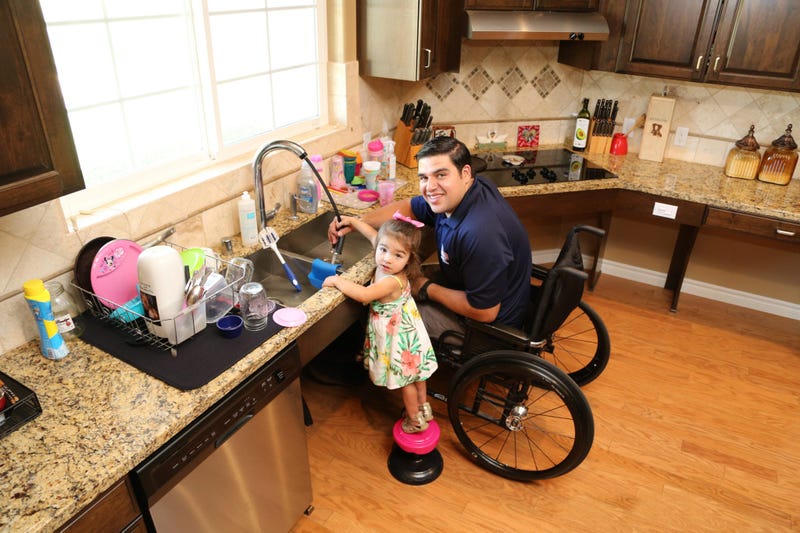 A wounded combat veteran who received a house from Homes For Our Troops washes dishes with his daughter