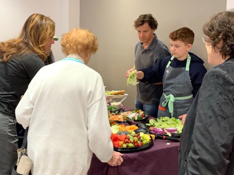 Haverford teen Avner Schwartz serves desserts he made to Holocaust survivors as part of his mitzvah project at the Jewish Family and Children's Services Center in Bala Cynwyd.