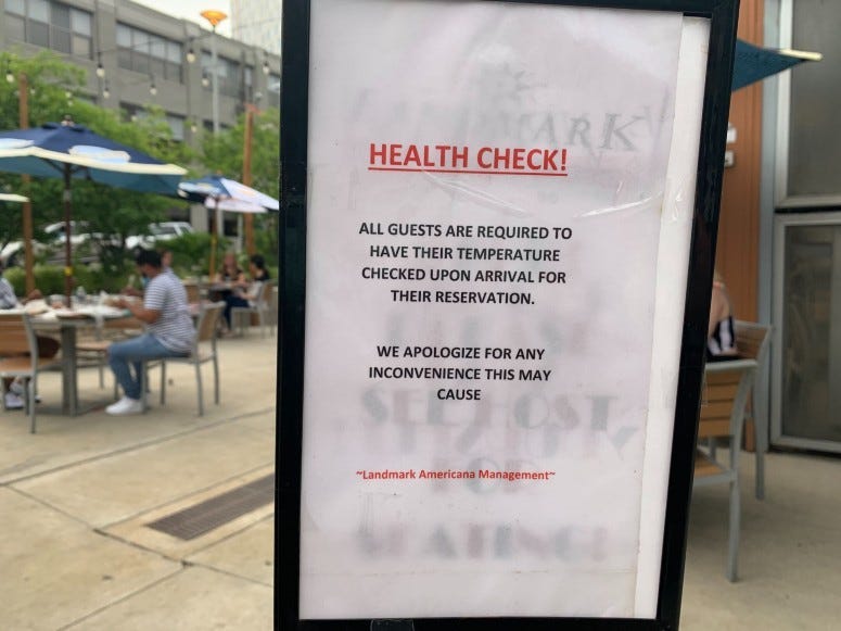 Sign in front of restaurant reminding guests to have their temperatures checked