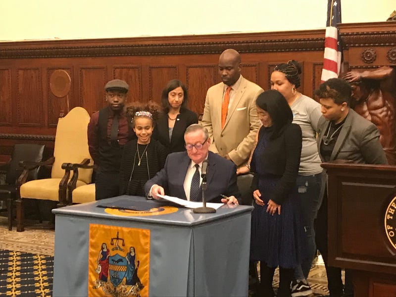 Mayor Jim Kenney, flanked by 10-yuear-old Itzela and Councilmember-at-Large Helen Gym, signs bills intended to protect transgender and gender nonbinary youth.
