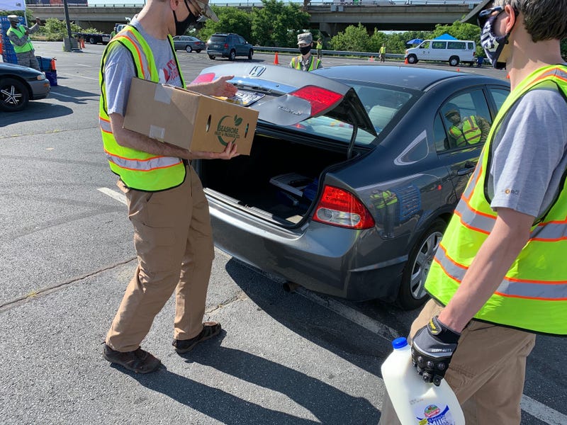 Philabundance volunteers give food to people waiting in the drive-thru line