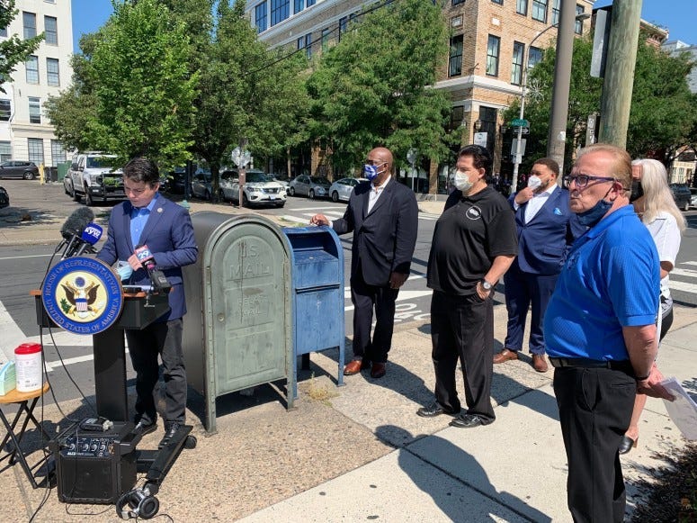 Congressman Brendan Boyle at the podium, and his colleagues and the postal workers union leader are in background