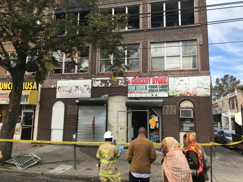 Firefighter and neighbors look on at the aftermath of a fatal fire on the 6500 block of Woodland Avenue.