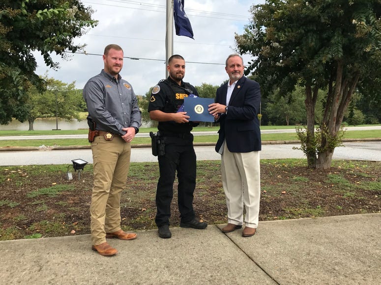 Duncan presents flag to Sheriff Chad McBride (left) and Roscoe's handler Master Deputy Matt Davis (middle) - Emily Gill