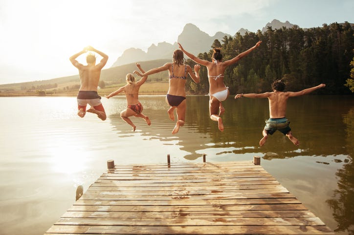 Young friends jumping into the lake off a pier