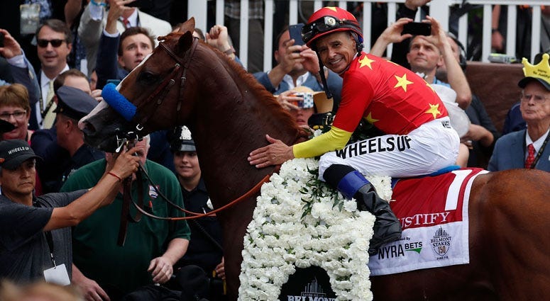Mike Smith aboard Justify poses for photos in the winner circle after winning the 150th Belmont Stakes and Triple Crown at Belmont Park on June 9, 2018.