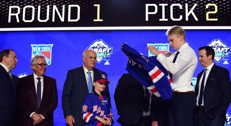 Kaapo Kakko puts on a team jersey after being selected as the No. 2 overall pick to the New York Rangers in the first round of the 2019 NHL Draft on June 21, 2019, at Rogers Arena in Vancouver, British Columbia.