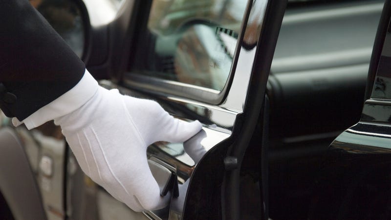 A white gloved hand opens a limousine door