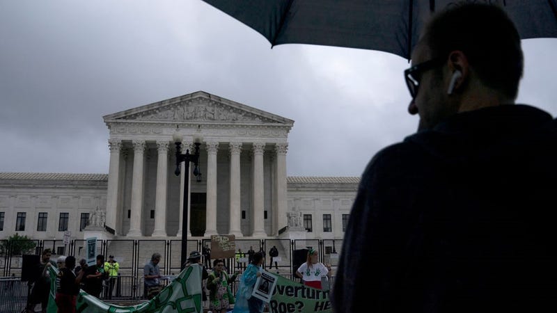 A man holding an umbrella watches as abortion-rights activists set up for a rally on June 23, 2022 in Washington, DC.