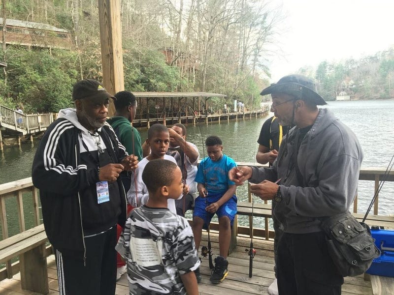 Officer Bruce Griggs (l) observes as the boys receive fishing lessons at YMCA Camp High HarboUr in Cartersville GA