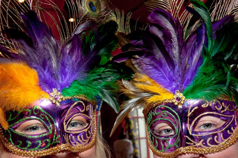 Women wearing purple, gold and green masks for Mardi Gras