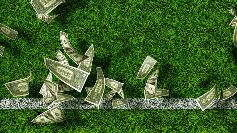 Dollar bills rain down onto a grass field