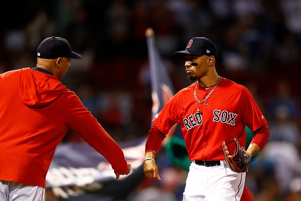 Red Sox OF Mookie Betts celebrates a victory with Alex Cora.