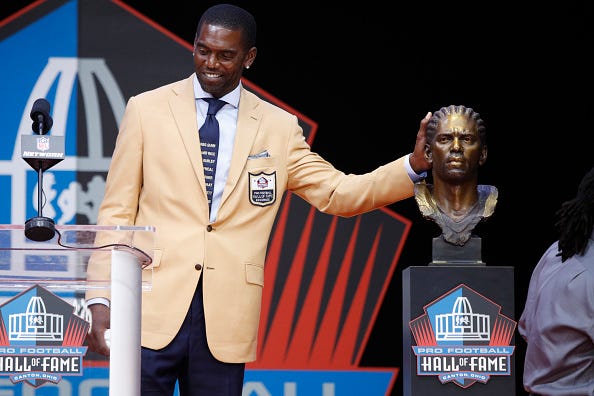 Randy Moss poses with his bust at the Pro Football Hall of Fame.