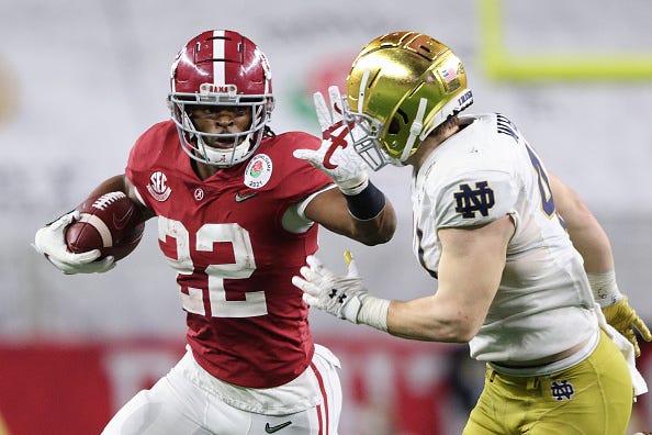 Najee Harris stiff arms a Notre Dame tackler