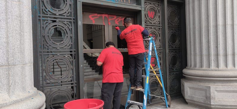 Workers repair smashed windows at Oakland City Hall.