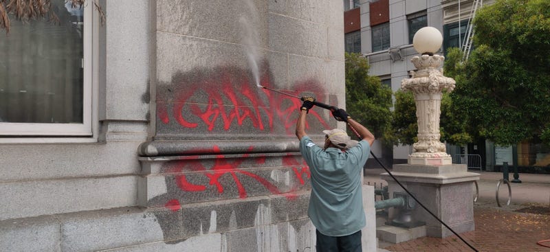Workers clean graffiti from Oakland City Hall.