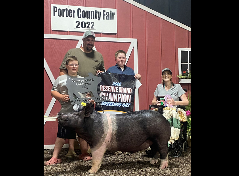 Four people and a pig stand with champion banners at the Porter County Fair