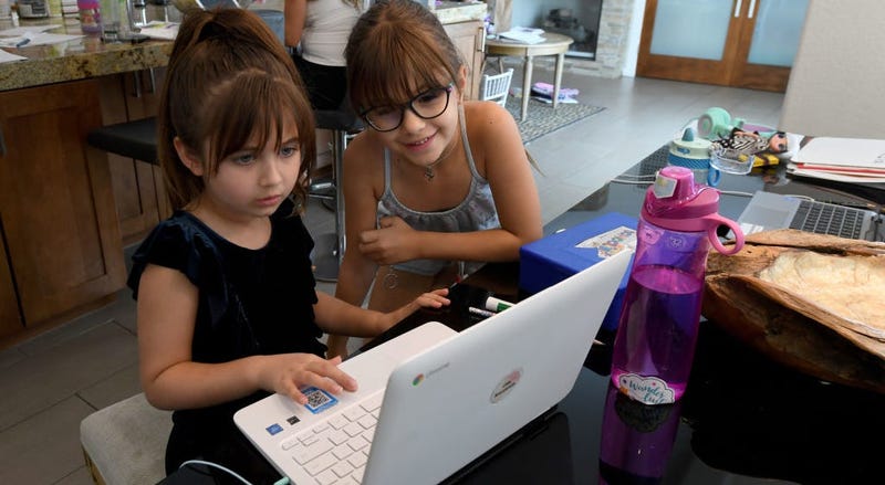 Two children sit in front of a computer doing their schoolwork.