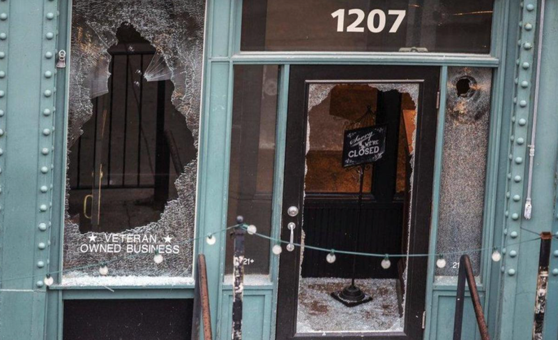 A "sorry we're closed" sign sits in the entrance surrounded by broken glass at The Hive, near where a man was shot to death during protests in May 20202. CHRIS MACHIAN/OMAHA WORLD-HERALD VIA AP
