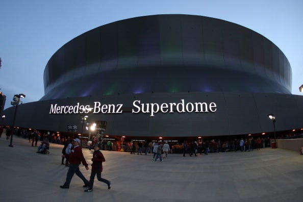 Fans walk by the Mercedes-Benz Superdome