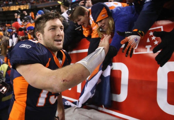 Tim Tebow high-fives fans at Mile High in Denver.