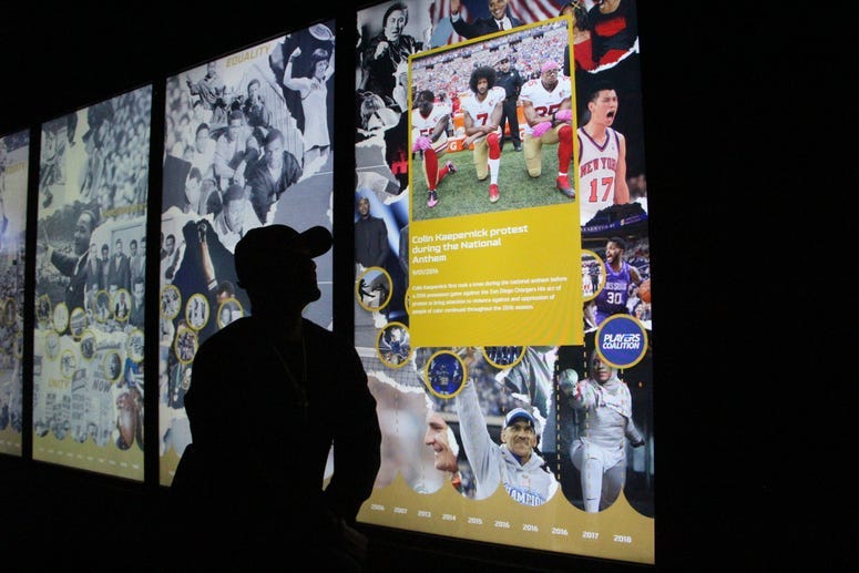 Big Tigger kneels in front of a social justice exhibit at the NFL Experience during the week of Super Bowl 53 in Atlanta