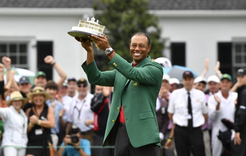 Tiger Woods celebrates with the green jacket and trophy after winning The Masters golf tournament