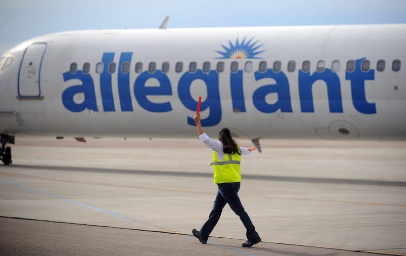 An Allegiant Airlines worker helps taxi a plane for takeoff during the last day of business for Allegiant Airlines