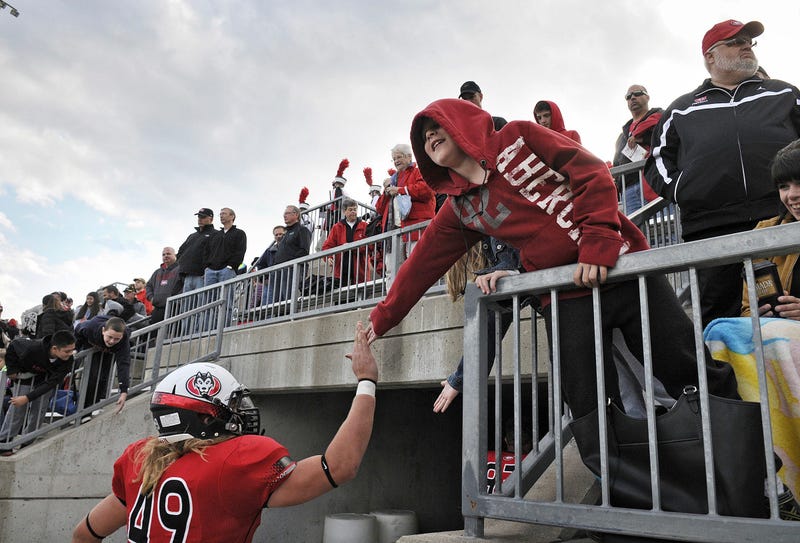 A young fan congratulates St. Cloud State University players as they leave the field after a game in 2014