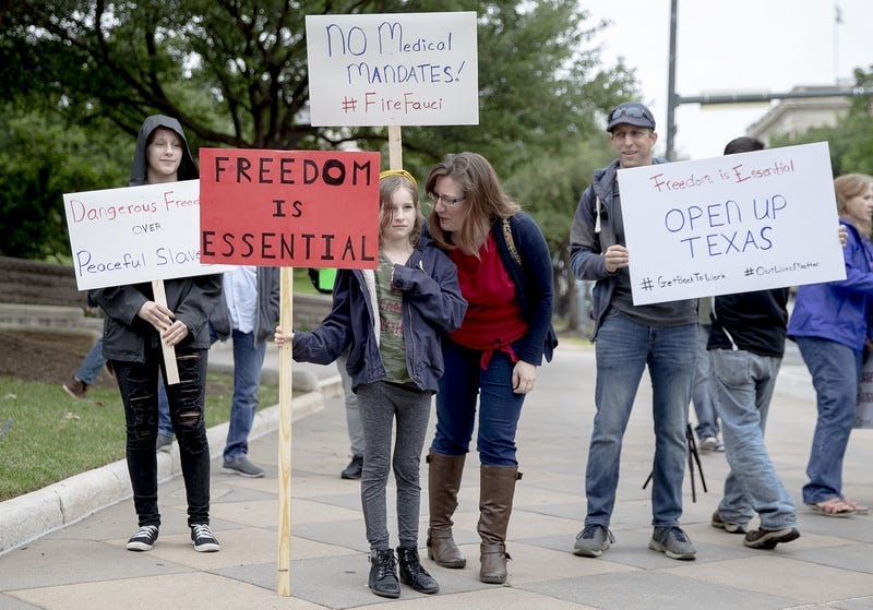 People hold up signs protesting government mandated shutdowns due to the coronavirus pandemic during a \"You Can't Close America Rally\" at the Texas capitol building on Saturday, April 18, 2020, in Austin, Texas.