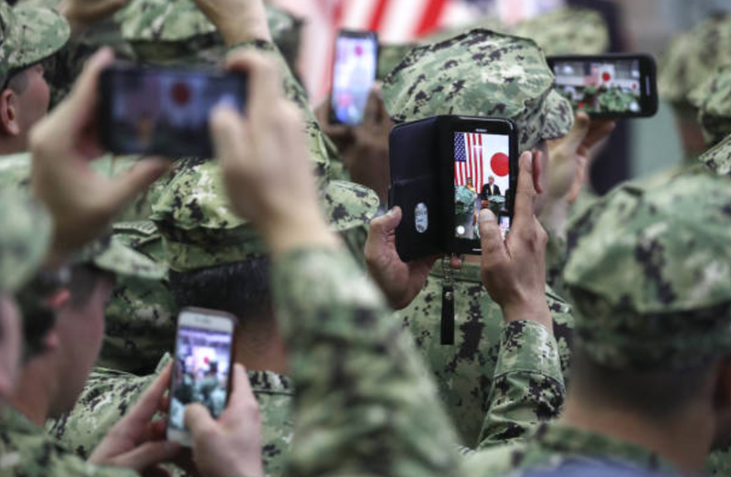 U.S. military personnel use smartphones to take photographs of U.S. President Donald Trump