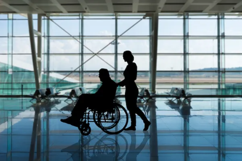 Woman pushing man in a wheelchair through an airport