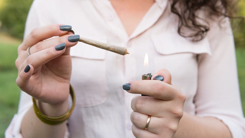 The young person smoking medical marijuana joint outdoors. The young woman smoke cannabis blunt, close-up.