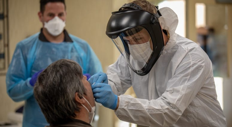 Sgt. Nicholas Shepherd (right), a practical nursing specialist assigned to Urban Augmentation Medical Task Force 352-2, and Jason Cavallaro, director of ambulatory operations at Cooper University Health Care, perform a swab test on a nursing home worker. Coronavirus