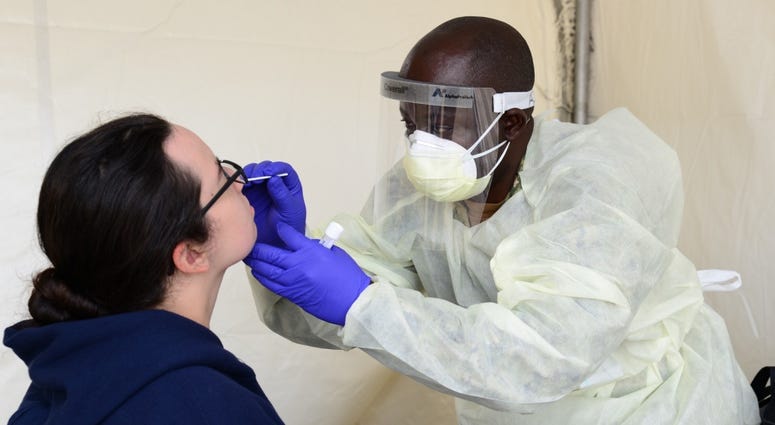 Hospital Corpsman 3rd Class Rene Azombi, a Navy reservist temporarily assigned to Navy Medicine Readiness and Training Command Great Lakes (NMRTC) to assist with COVID-19 screening efforts, conducts a nasal swab on a recruit. Hospital Corpsman 3rd Class Rene Azombi, a Navy reservist temporarily assigned to Navy Medicine Readiness and Training Command Great Lakes (NMRTC) to assist with COVID-19 screening efforts, conducts a nasal swab on a recruit.