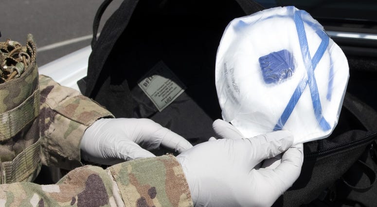 Senior Airman Jeffrey Clark, a 48th Security Forces Squadron response force leader, puts a respirator mask inside a COVID-19 response kit at Royal Air Force Lakenheath, England, April 16, 2020. Coronavirus