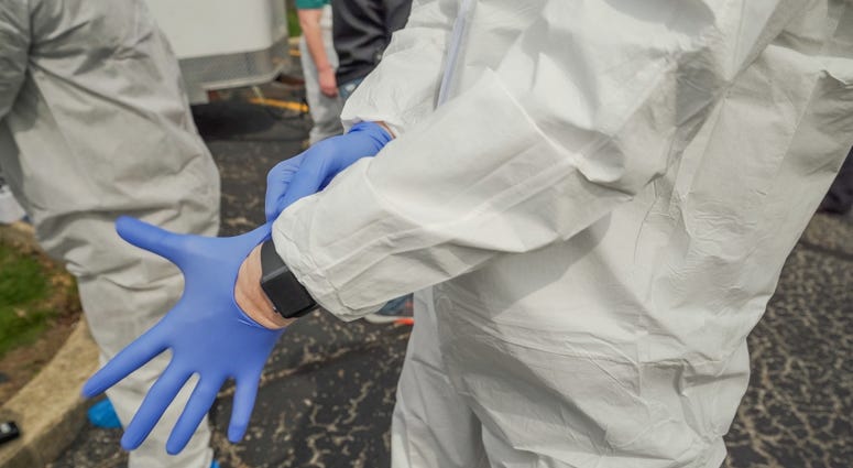 A soldier with the 708th Medical Company puts on a medical examining glove at Park Glen Apartments in Taylorville, Illinois. Coronavirus