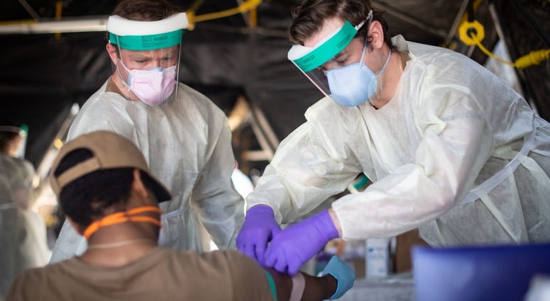 Hospital Corpsman 2nd Class Shane Miller, left, and hospital Corpsman 2nd Class Austin Kelly, both assigned to Fleet Surgical Team 9, draw blood from a sailor assigned to the guided-missile destroyer USS Kidd. Coronavirus