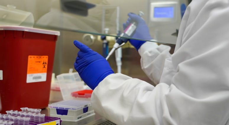 NHRC Operational Infectious Diseases lab technician aliquotting specimens for COVID-19 testing within the biological safety cabinet, known as the "hood." NHRC Operational Infectious Diseases lab technician aliquotting specimens for COVID-19 testing within the biological safety cabinet, known as the "hood."