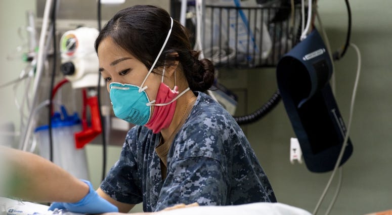 Lt. j.g. Joyce Sim, from Seoul, Korea, adjusts a pillow while treating a patient aboard the hospital ship USNS Mercy (T-AH 19). Coronavirus