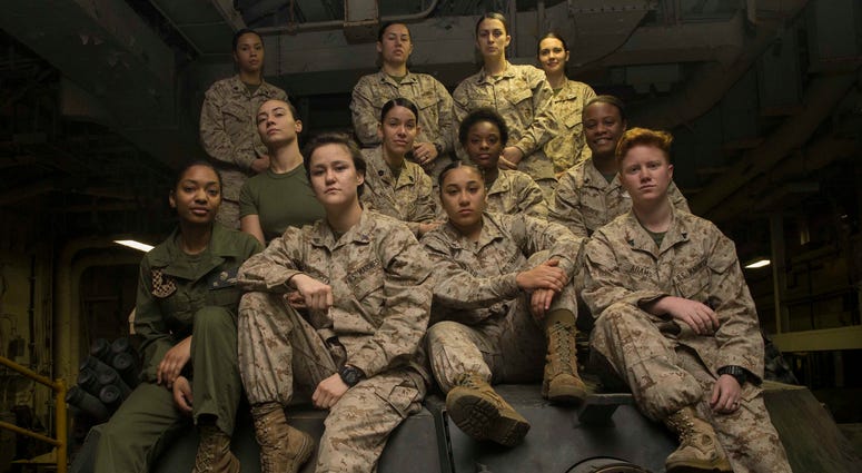 Female Engagement Team Marines pose atop an M1A1 Abrams Main Battle Tank turret after completing training