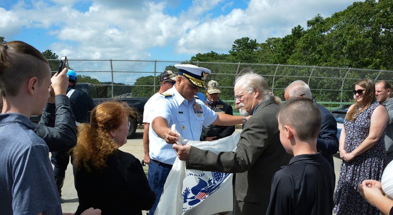 Coast Guard Adm. Andy Tiongson presents Stephen and Bradley Finch with the Coast Guard Ensign