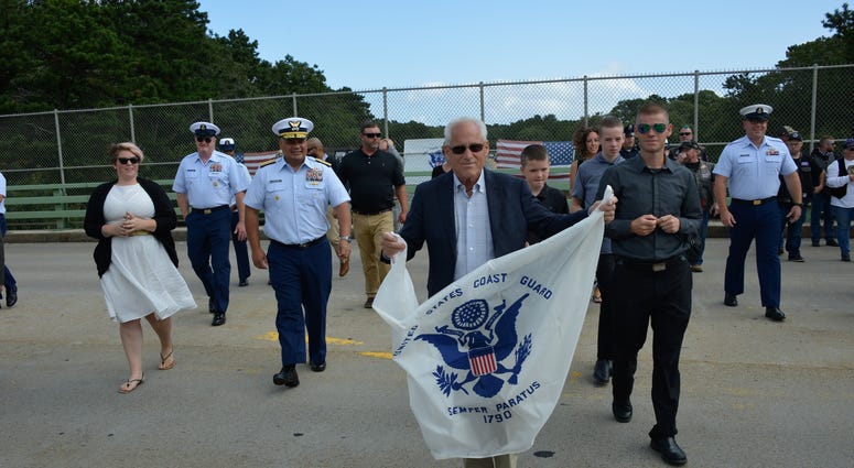 Bradley Finch crosses a Cape Cod bridge holding a Coast Guard Enslgn