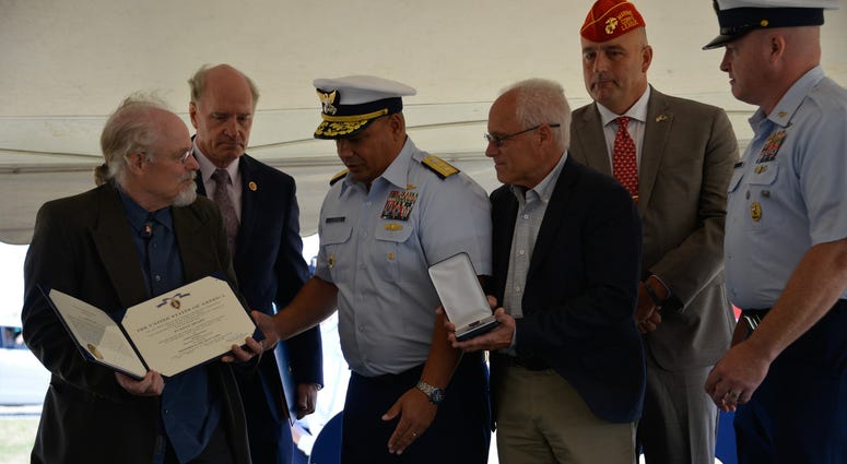 Coast Guard Adm. Andy Tiongson prepares to pose for a photo with Stephen and Bradley Finch