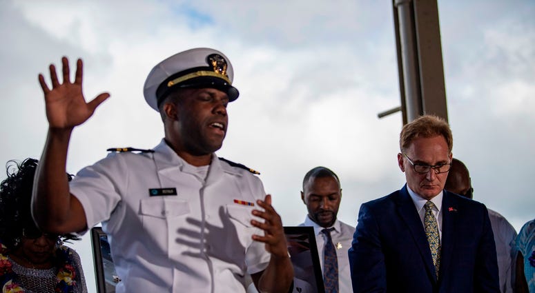Acting Secretary of the Navy Thomas B. Modly, right, bows his head during an invocation following the unveiling of the new Ford-class aircraft carrier USS Doris Miller (CVN 81)