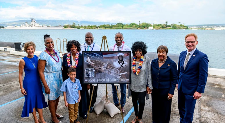 Acting Secretary of the Navy Thomas B. Modly, right, poses for a photo next to a graphic illustration of the new Ford-class aircraft carrier USS Doris Miller (CVN 81)