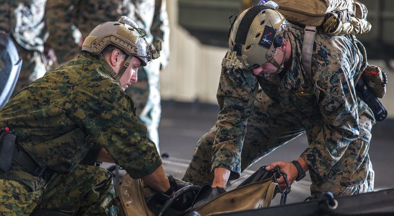 Marines pack equipment in a combat rubber raiding craft in preparation for search and rescue operations