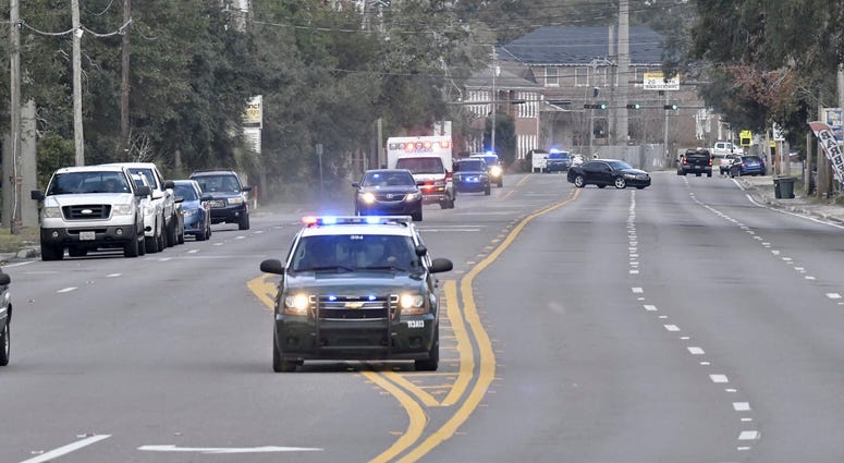 Police cars escort an ambulance after a shooter open fire inside the Pensacola Air Base, Friday, Dec. 6, 2019 in Pensacola, Fla. The US Navy is confirming that a shooter is dead and several injured after gunfire at the Naval Air Station in Pensacola.